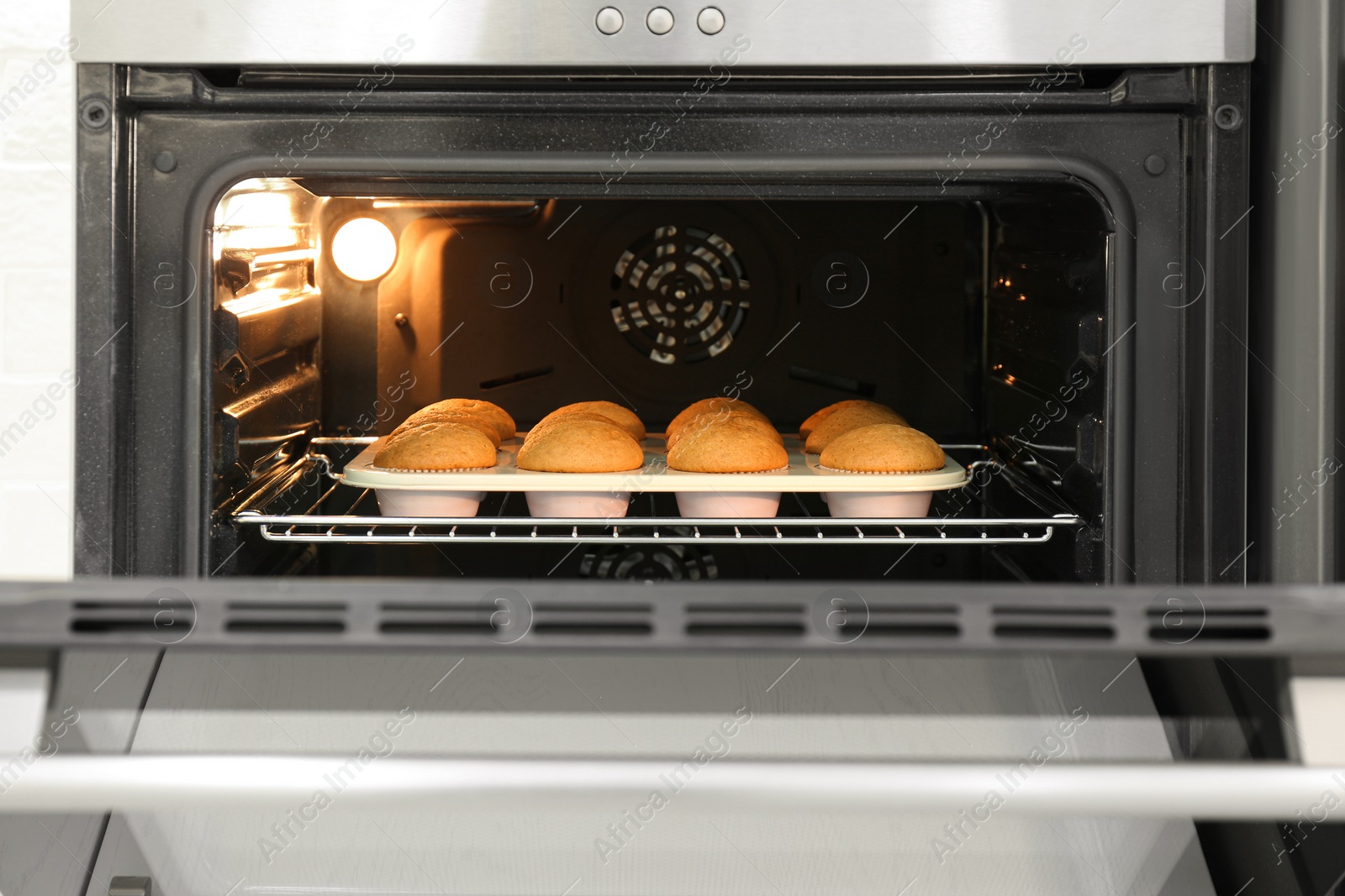 Photo of Baking pan with cupcakes in modern oven