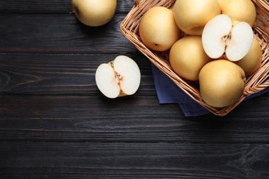 Photo of Cut and whole apple pears on black wooden table, flat lay. Space for text