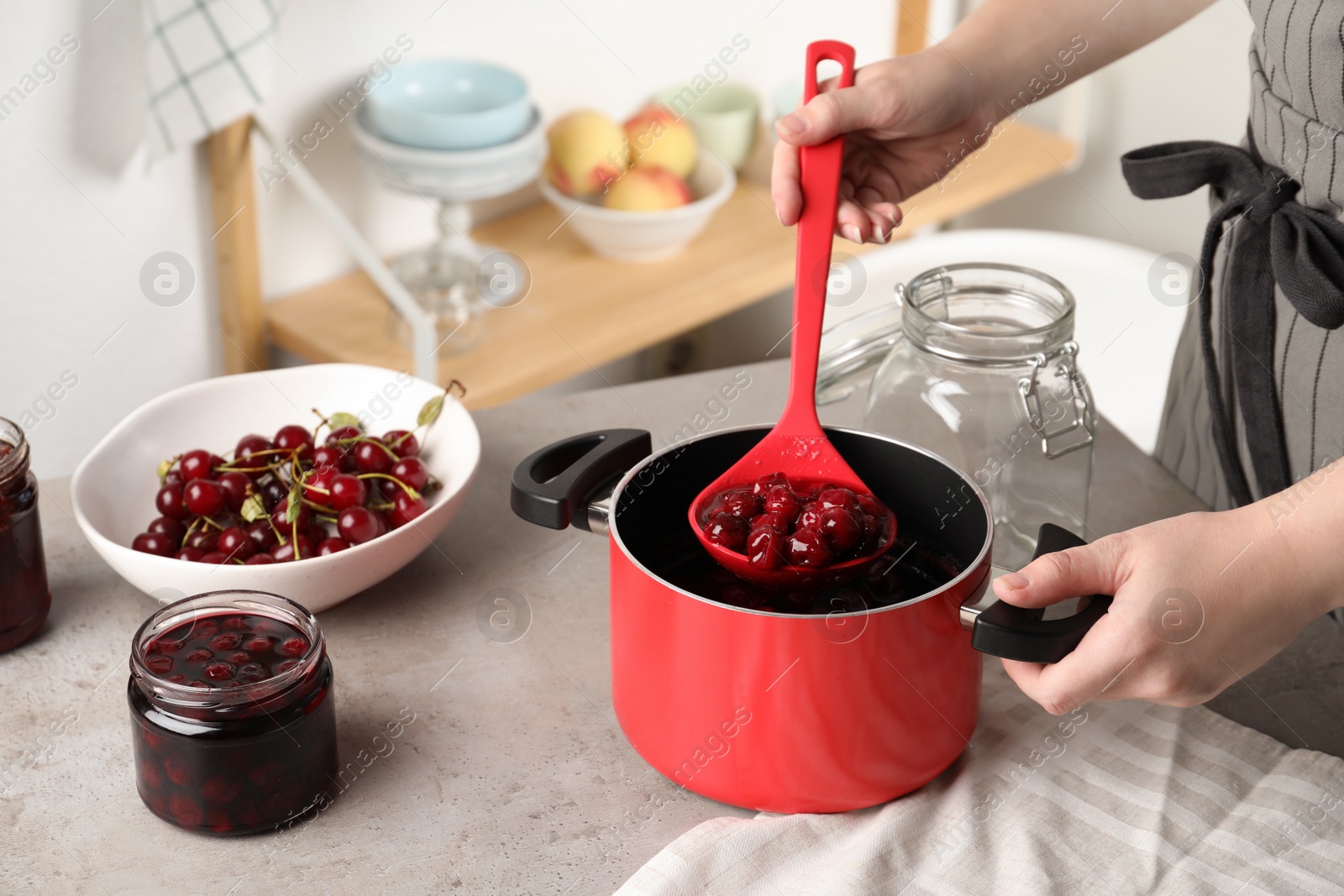 Photo of Woman making pickled cherries at table indoors, closeup