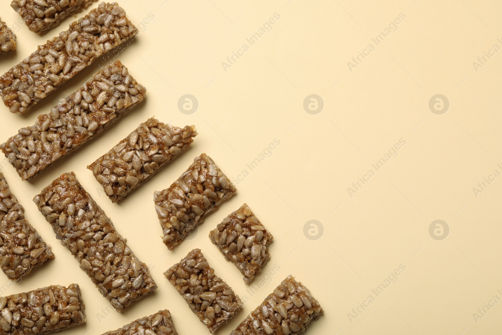 Photo of Pieces of delicious kozinaki bars on beige background, flat lay. Space for text