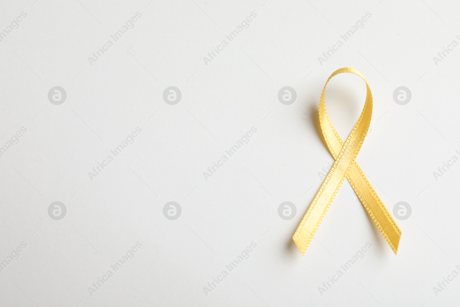 Photo of Yellow ribbon on white background, top view. Cancer awareness