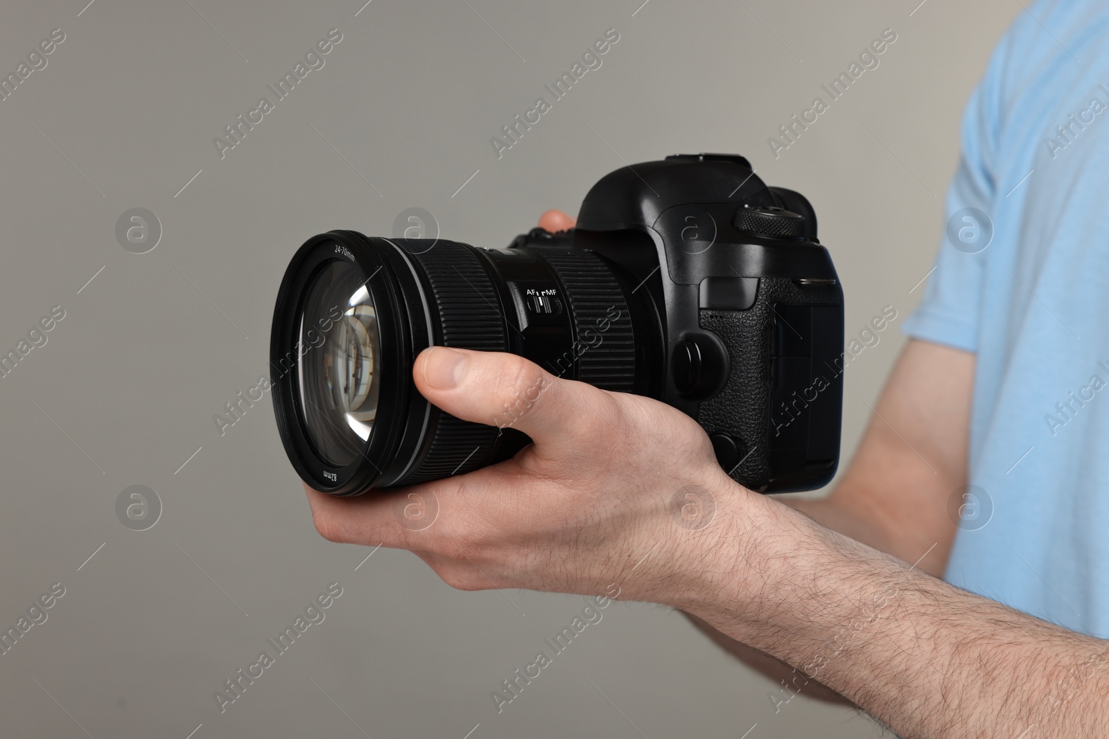 Photo of Photographer holding camera on grey background, closeup