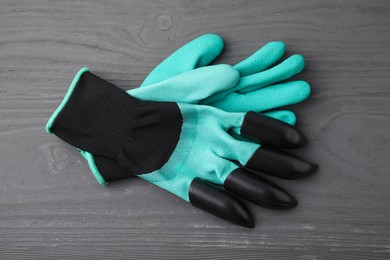 Pair of claw gardening gloves on grey wooden table, top view