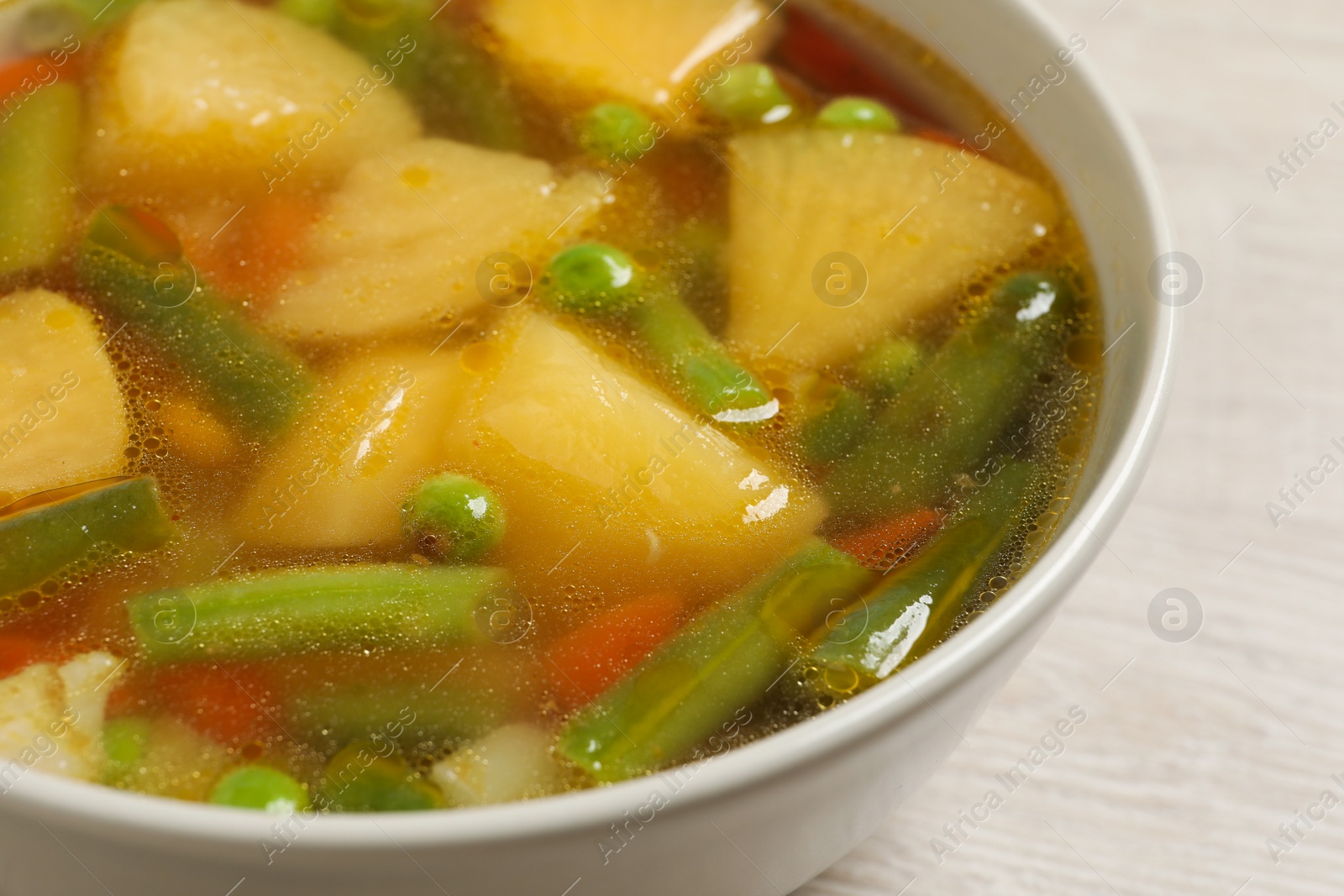 Photo of Bowl of delicious turnip soup on wooden table, closeup