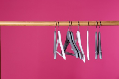 Wooden rack with clothes hangers on color background, space for text