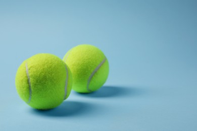 Photo of Two tennis balls on light blue background, space for text