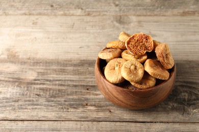 Bowl with tasty dried figs on wooden table. Space for text