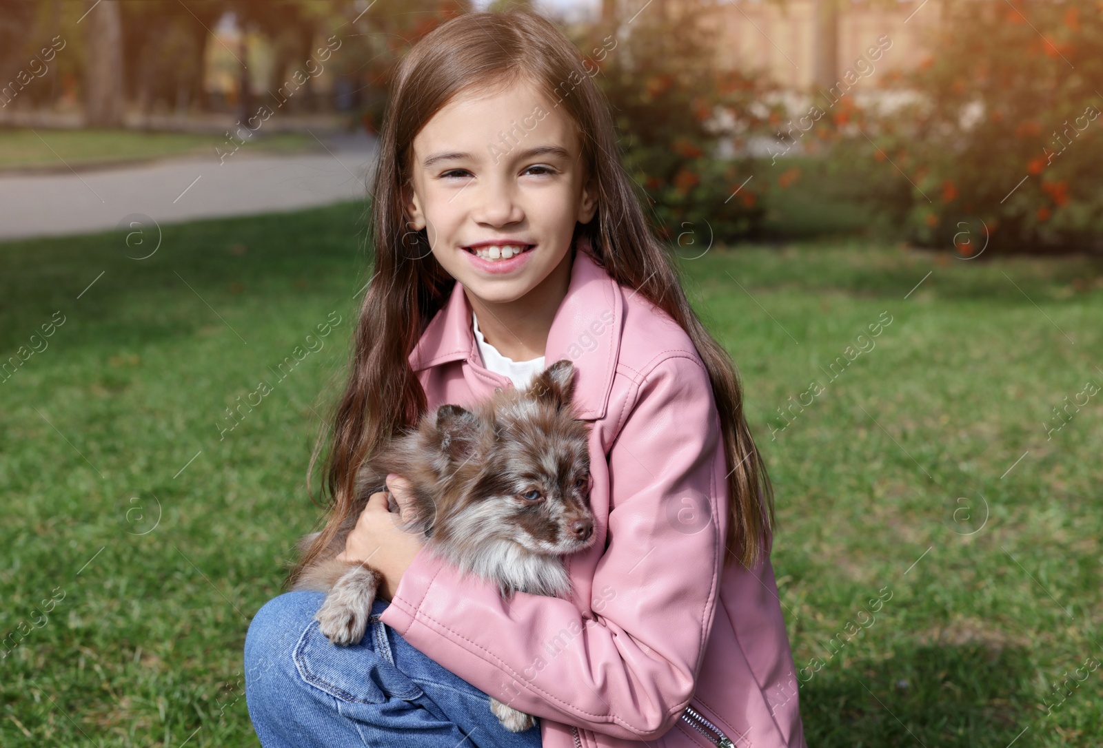 Photo of Little girl with her cute dog in park. Autumn walk