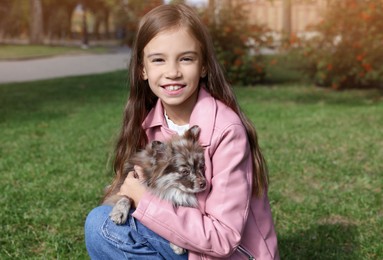 Little girl with her cute dog in park. Autumn walk