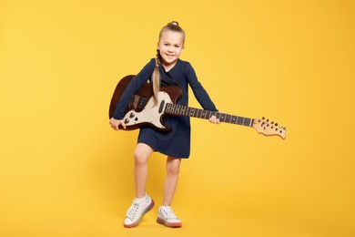 Photo of Happy girl with electric guitar on yellow background