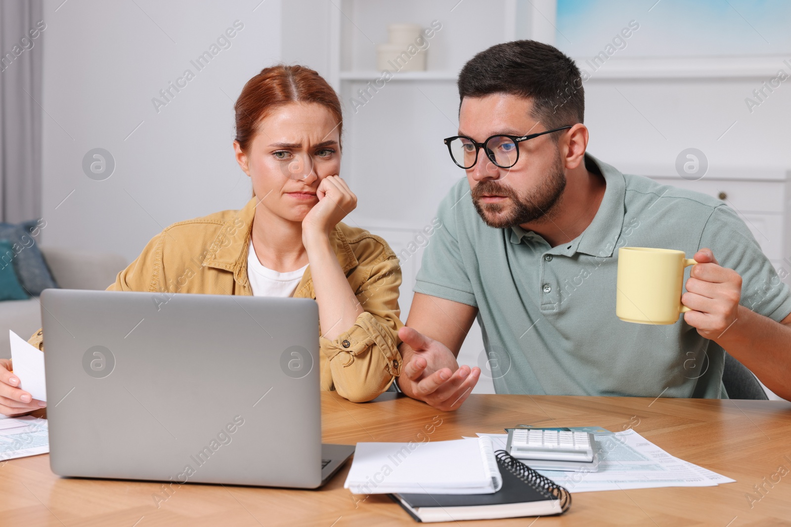 Photo of Emotional couple doing taxes at table in room