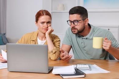 Emotional couple doing taxes at table in room