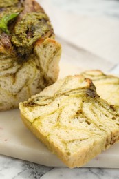 Photo of Freshly baked pesto bread on white marble table, closeup