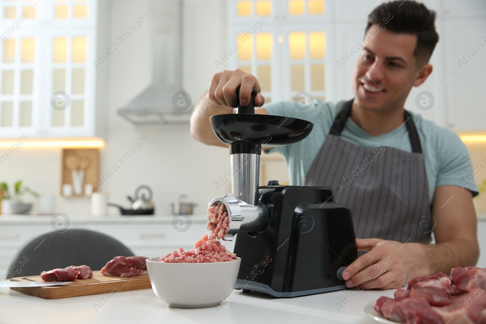 Photo of Man using modern meat grinder in kitchen