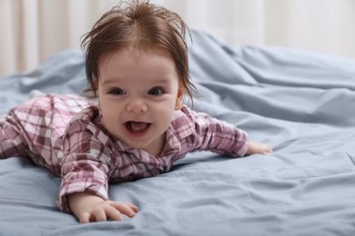 Photo of Cute little baby in pajamas on bed indoors. Space for text