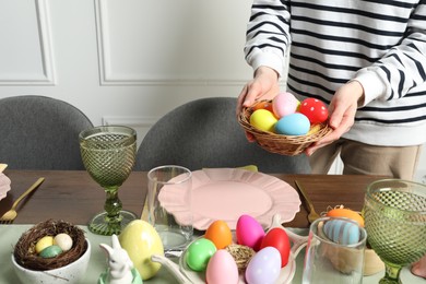 Photo of Woman setting table for festive Easter dinner at home, closeup