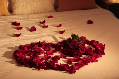 Honeymoon. Heart made with roses and beautiful petals on bed