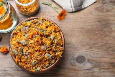 Bowl of dry calendula flowers and bottles with tincture on wooden table, flat lay. Space for text