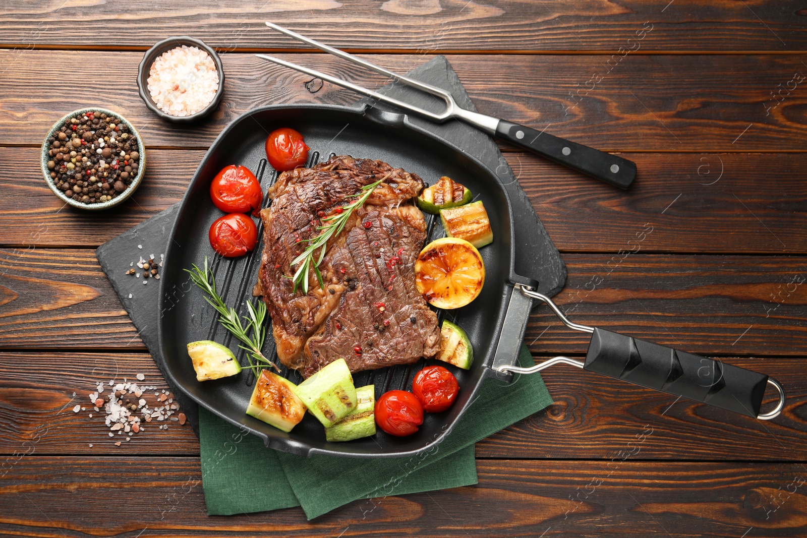 Photo of Delicious grilled beef steak and vegetables served on wooden table, flat lay