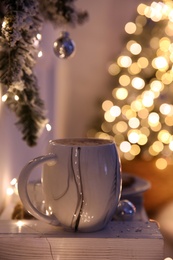 Photo of Cup of tasty hot drink and Christmas tree branch indoors. Space for text