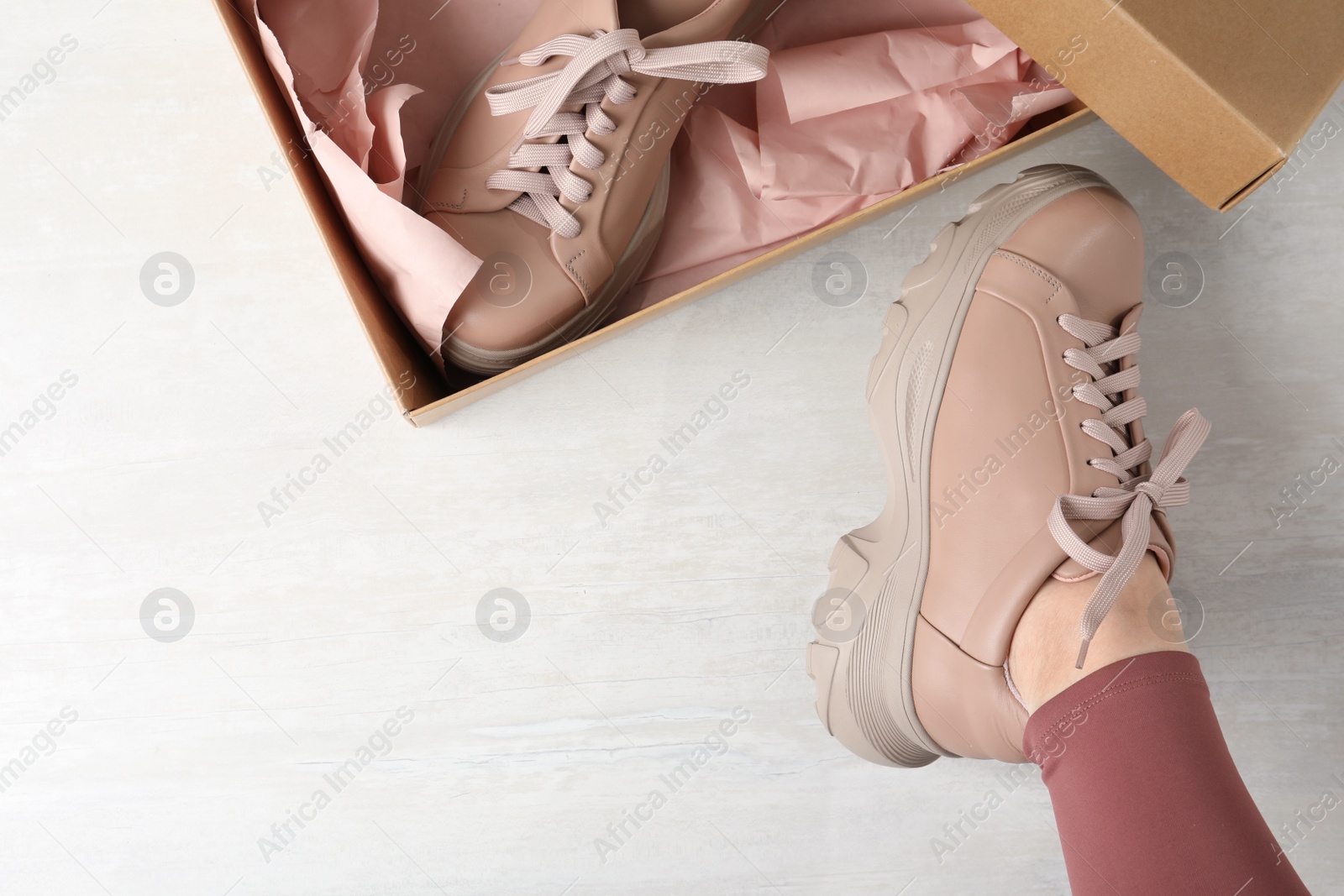 Photo of Young woman trying on shoes indoors, top view. Space for text