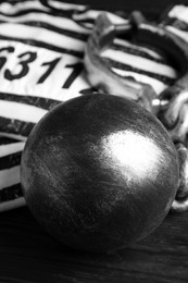 Photo of Prisoner ball with chain on black wooden table, closeup