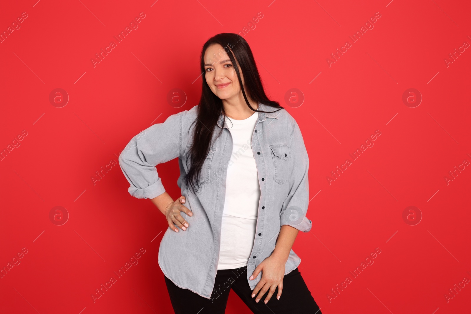 Photo of Beautiful overweight woman with charming smile on red background