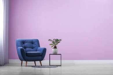 Photo of Stylish comfortable armchair near color wall