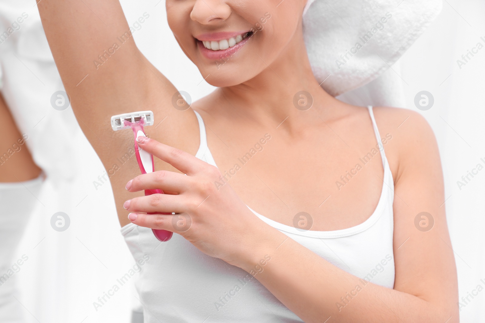 Photo of Beautiful young woman shaving armpit at home, closeup