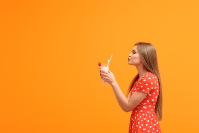 Photo of Young woman with glass of delicious milk shake on color background