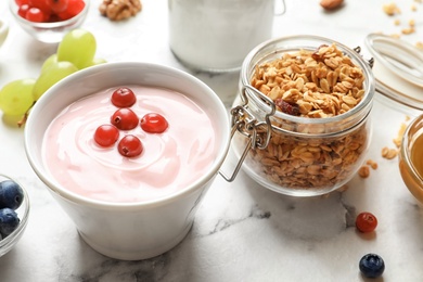 Photo of Bowl with yogurt, berries and granola on table