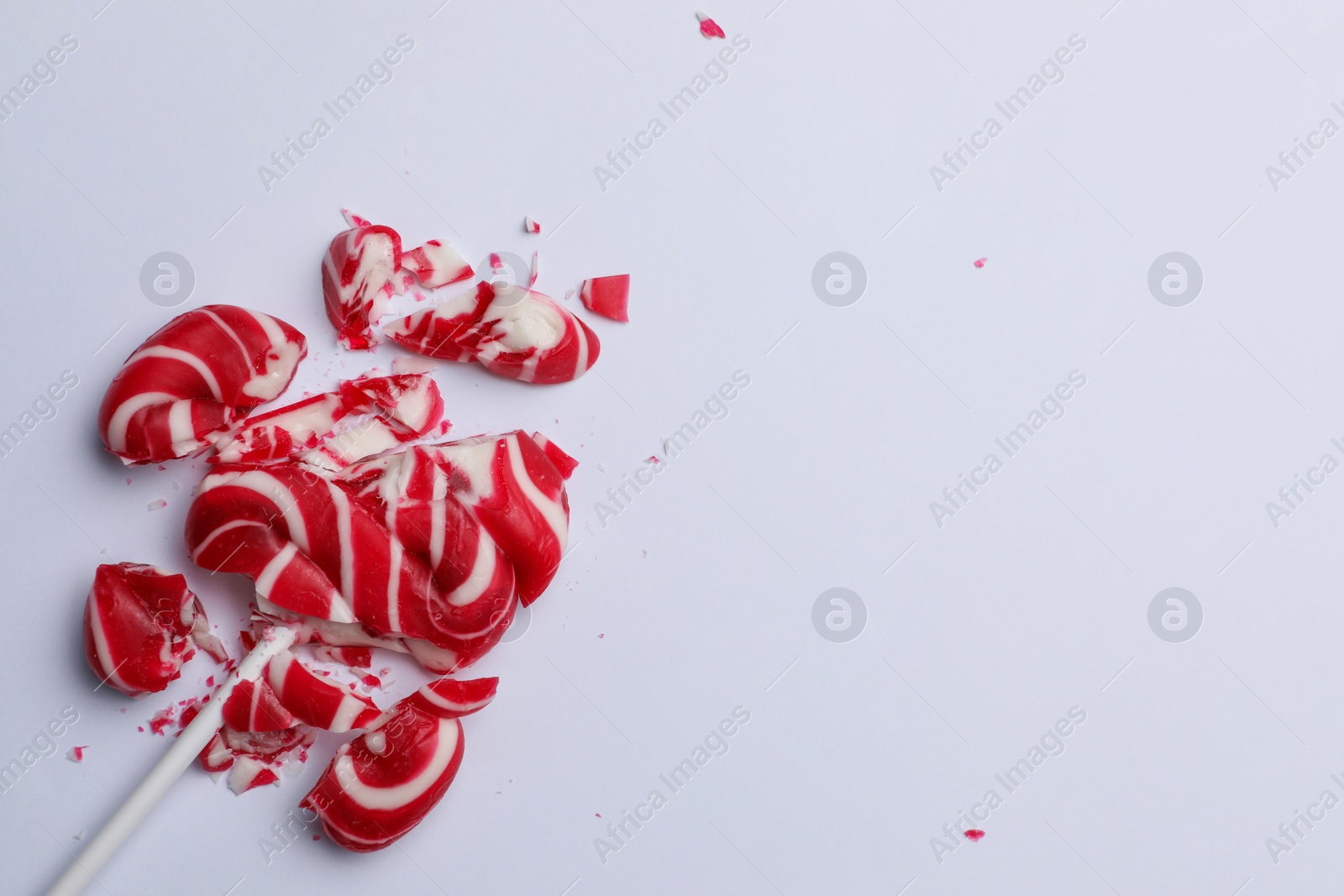 Photo of Smashed sweet lollipop on light background, top view. Space for text