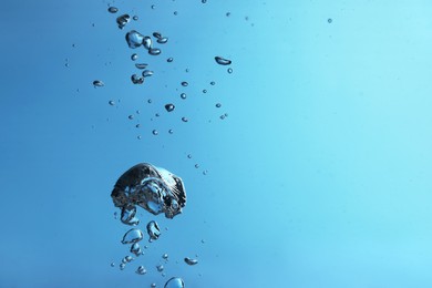 Air bubbles in water on light blue background. Space for text