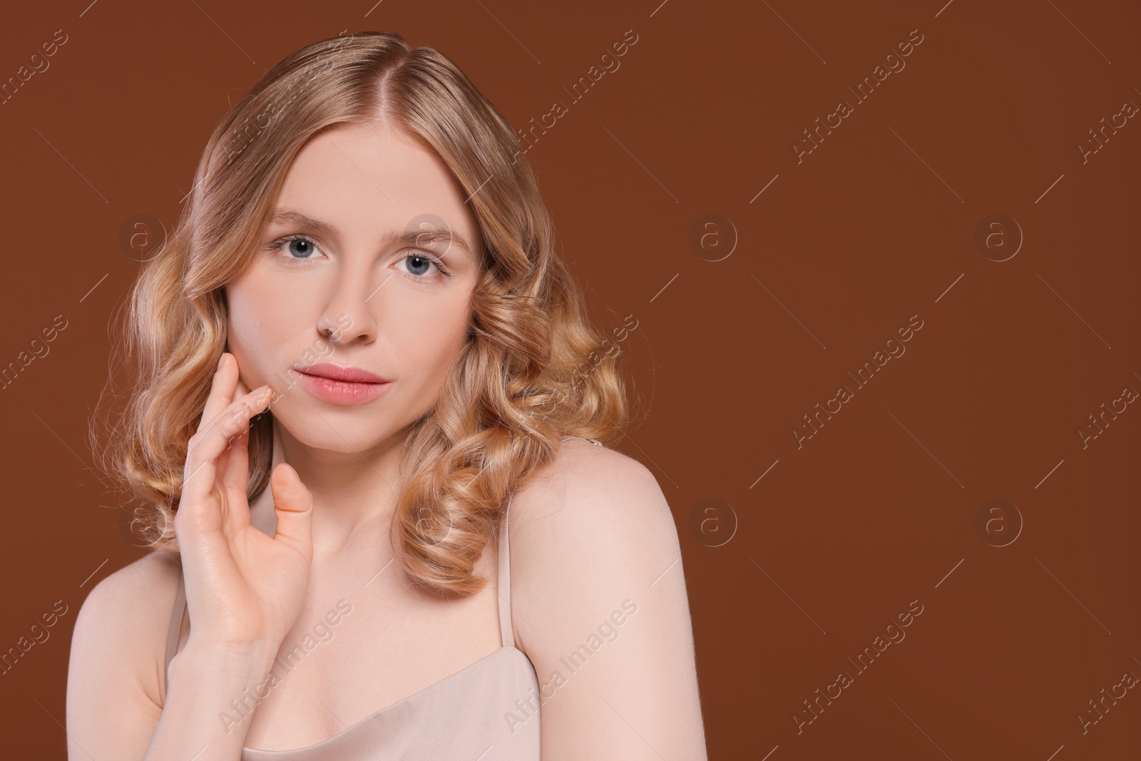 Photo of Portrait of beautiful woman with blonde hair on brown background. Space for text