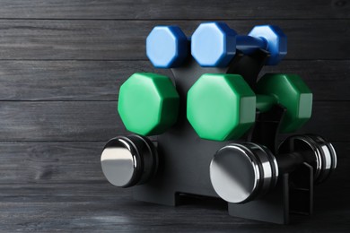 Photo of Rack with different dumbbells on black wooden background