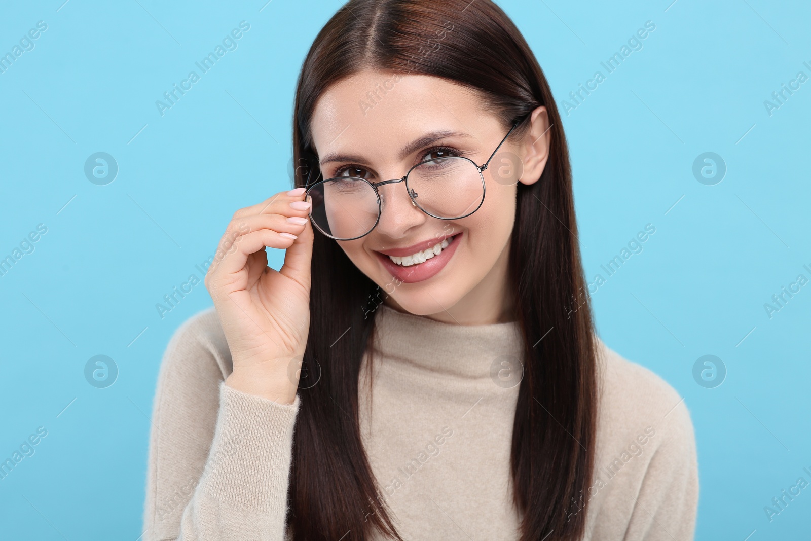 Photo of Portrait of smiling woman in stylish eyeglasses on light blue background