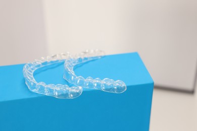 Transparent dental aligners on beige background, closeup. Space for text