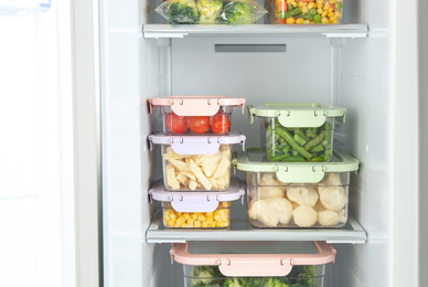 Photo of Containers with different frozen vegetables in refrigerator