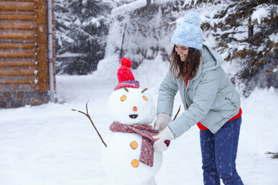 Photo of Happy woman making snowman outdoors. Winter vacation