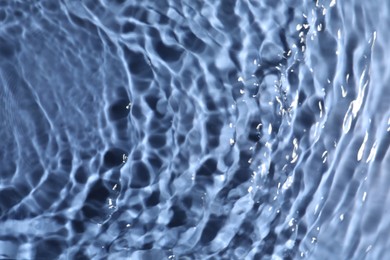 Photo of Closeup view of water with rippled surface on blue background