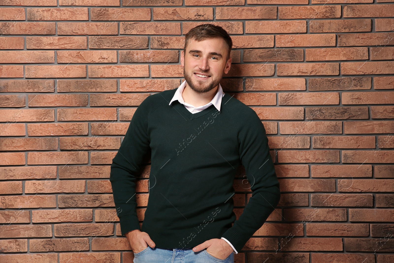 Photo of Handsome young man in warm sweater near brick wall