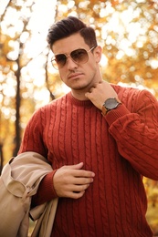 Handsome man walking in park on autumn day