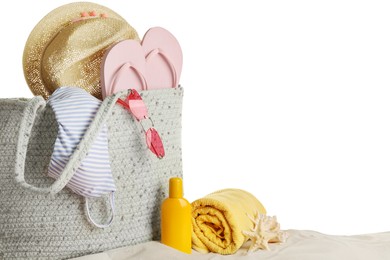 Bag with different beach objects on sand against white background