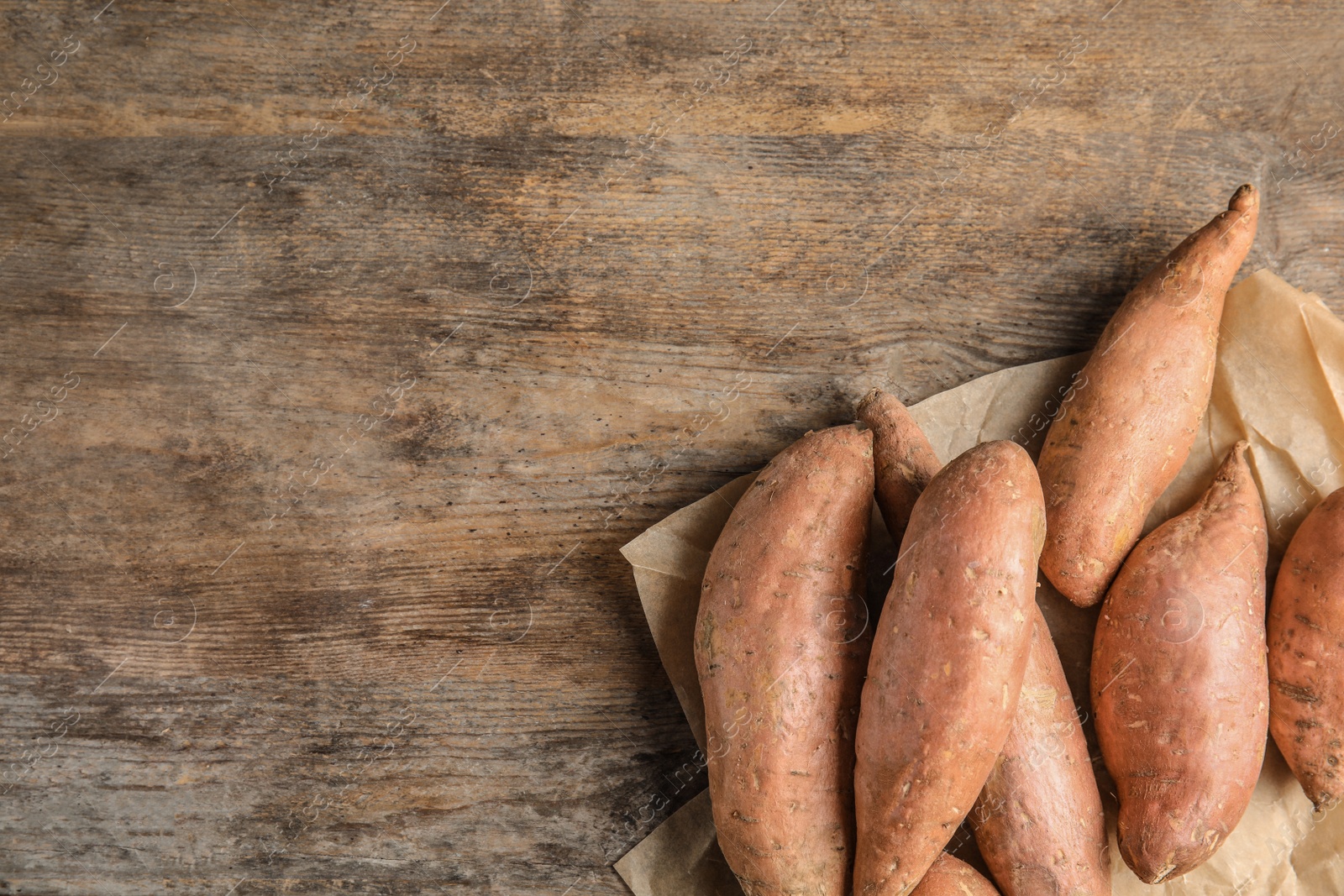 Photo of Flat lay composition with sweet potatoes and space for text on wooden background