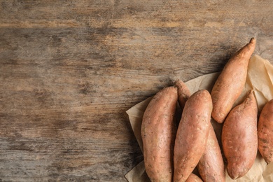 Photo of Flat lay composition with sweet potatoes and space for text on wooden background