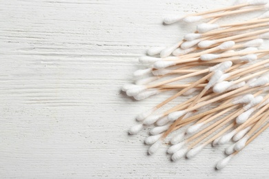 Photo of Pile of cotton swabs on white wooden background, top view. Space for text