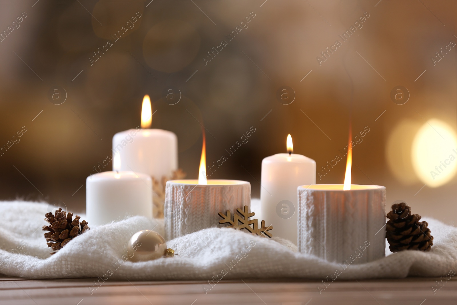 Photo of Composition with candles in ornate holder on wooden table against blurred background. Christmas decoration