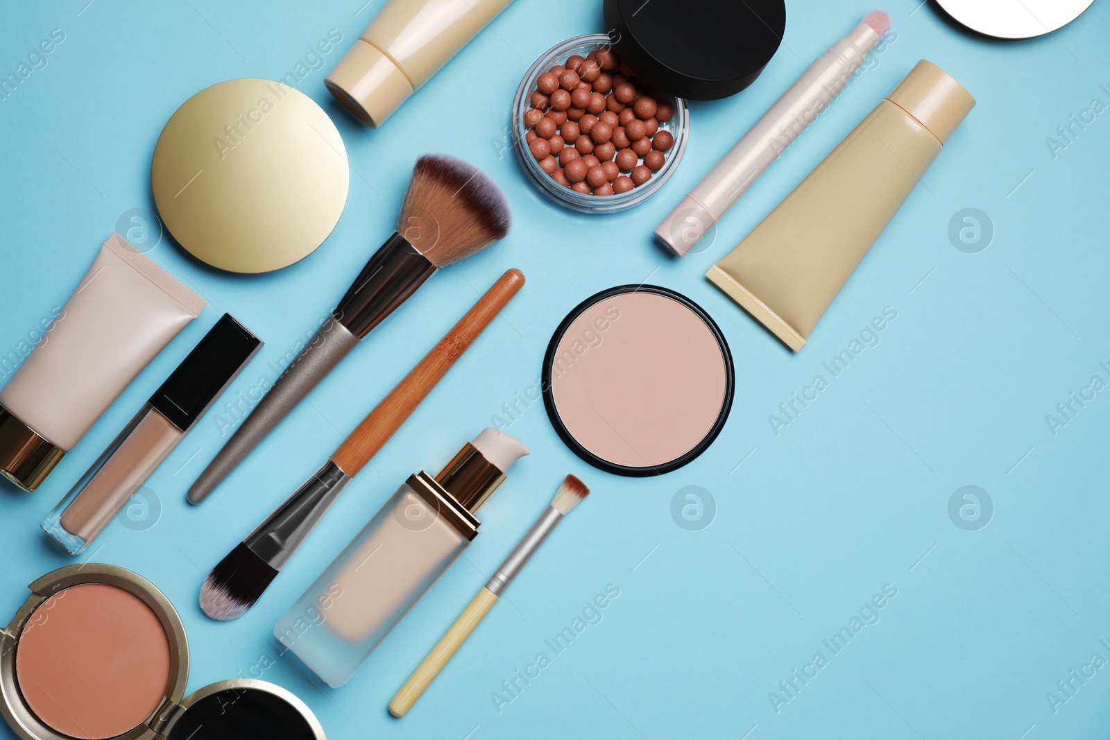 Photo of Face powders and other decorative cosmetic products on light blue background, flat lay