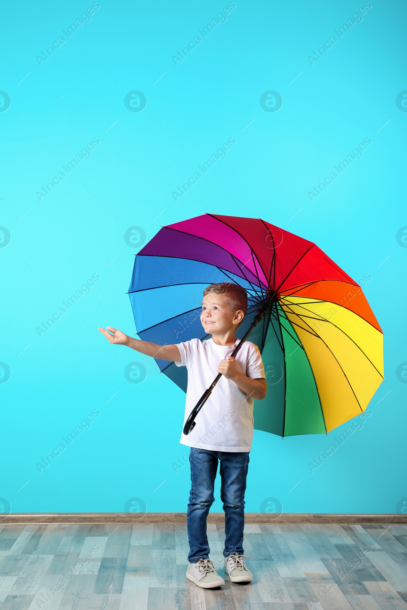 Photo of Little boy with rainbow umbrella near color wall