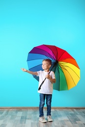 Photo of Little boy with rainbow umbrella near color wall